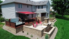 Grey house with red awning and chairs on a stone deck