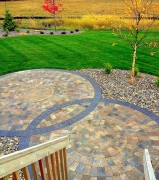 Overlapping radial brick pattern patio surrounded by loose rocks