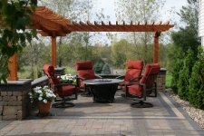 Square stone patio with stained wood pergola and seating area