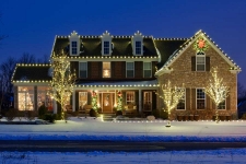 Brick house with lights around roof and front yard trees