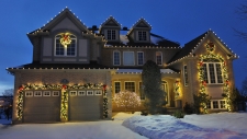 Snowy front yard of house trimmed with wreaths and lights